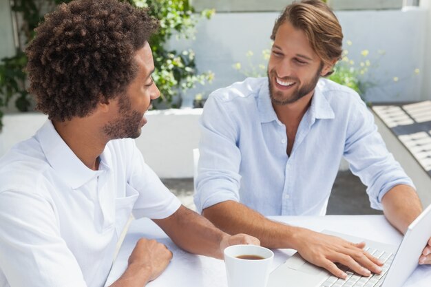 Dois amigos aproveitam o café junto com o laptop