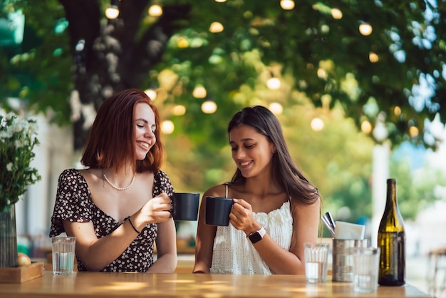 Dois amigos bebendo café mulheres tinindo com xícaras de café