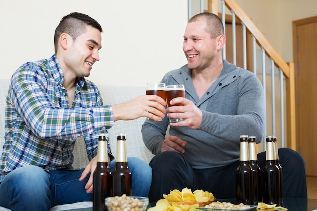 Foto dois amigos bebendo cerveja em casa