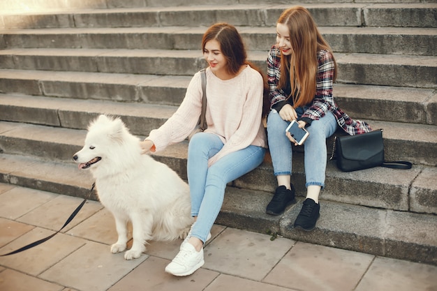 dois amigos bonitos e brilhantes sentado na cidade ensolarada de primavera com cachorro