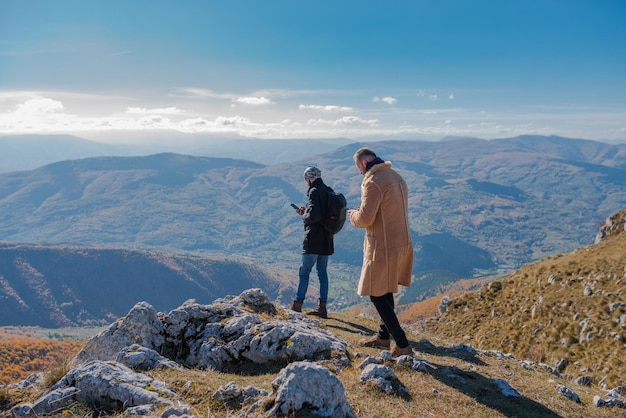 Dois amigos caminhantes procurando um telefone celular verificando um mapa para uma rota de caminhada