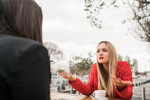 Foto dois amigos com raiva discutindo enquanto está sentado na cafeteria.