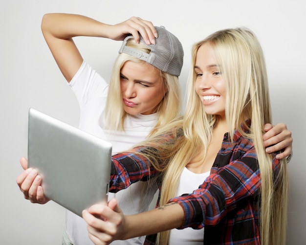 Dois amigos de garotas hipster tomando selfie com tablet digital