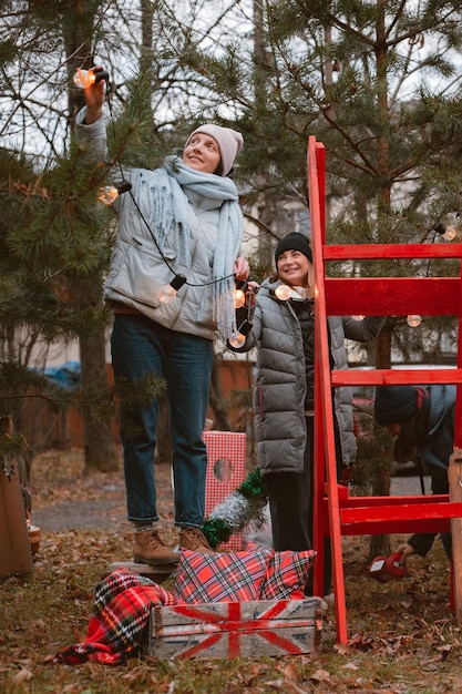 Dois amigos decoram árvores de Natal antes de celebrar o ano novo de 2022 ao ar livre para uma festa