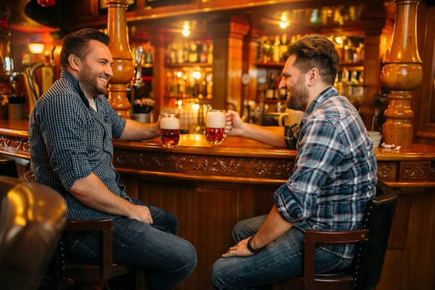 Dois amigos do sexo masculino bebem cerveja no balcão de um bar