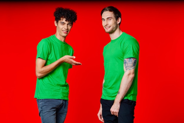 Dois amigos em camisetas verdes diversão comunicação fundo vermelho