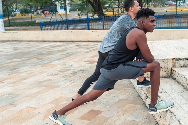 Dois amigos em roupas esportivas, estendendo-se na rua