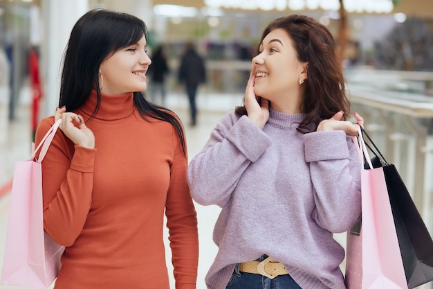 Dois amigos fazendo compras no shopping, posando com surpresa e animado