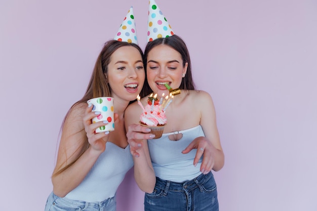 Dois amigos felizes comemorando aniversário em chapéus de festa