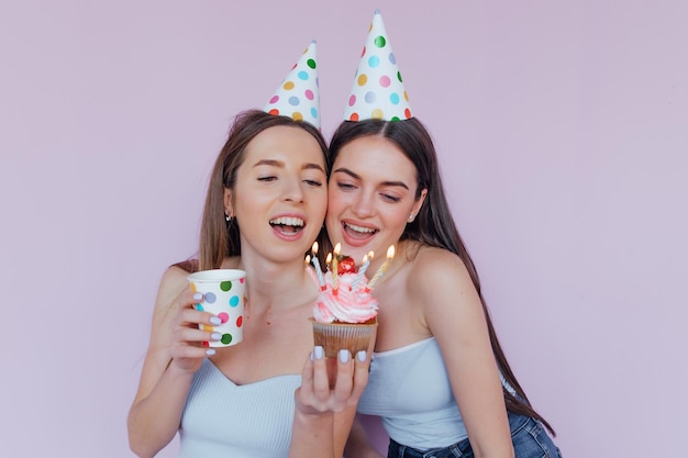 Dois amigos felizes comemorando aniversário em chapéus de festa