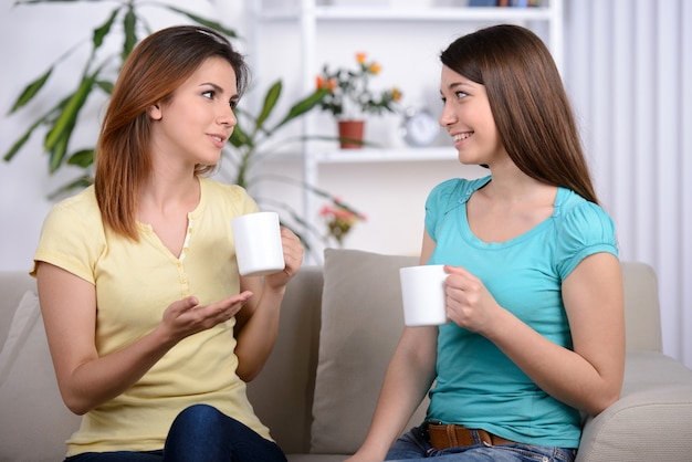 Dois amigos fêmeas novos felizes com copos de café.