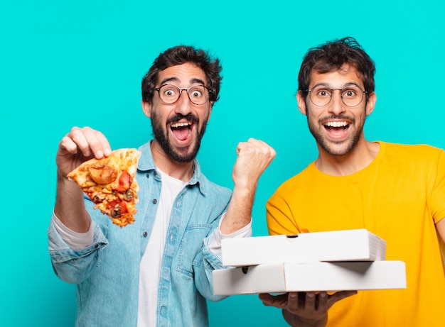 Dois amigos hispânicos comemorando uma vitória bem-sucedida e segurando pizzas para levar