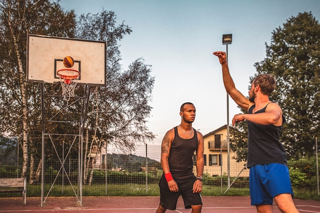 Dois amigos jogam basquete em uma quadra ao ar livre. jogadores de basquete jovens.