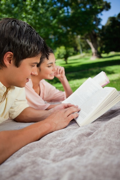 Dois amigos lendo livros enquanto deitados em um parque