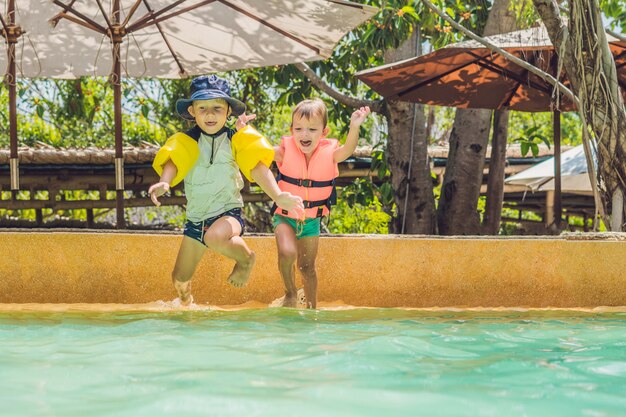 Dois amigos meninos pulando na piscina