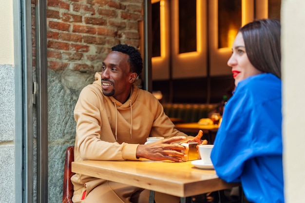 Dois amigos multiétnicos tomando um café juntos, sentados à mesa