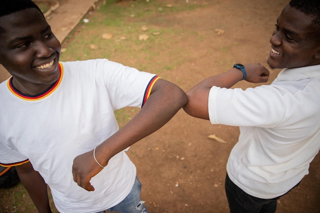 Dois amigos na África cumprimentando uns aos outros com cotovelos para reduzir o contato durante a pandemia de coronavírus novo conceito normal
