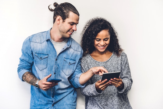 Foto dois amigos relaxam usam a tecnologia juntos do smartphone, verificando aplicativos sociais na parede da parede.