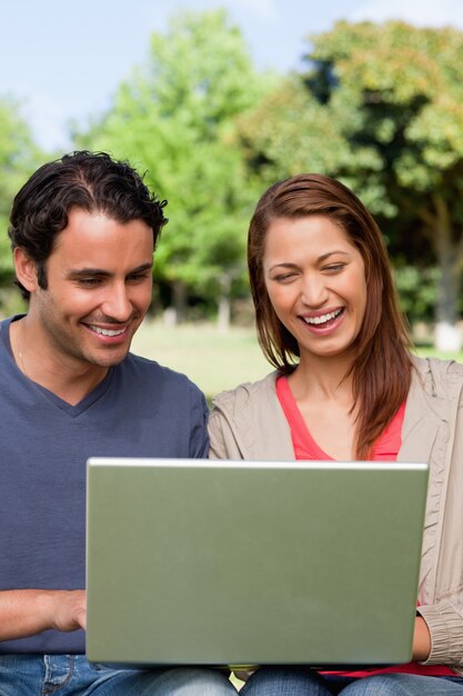 Dois amigos riem enquanto observam algo em um tablet