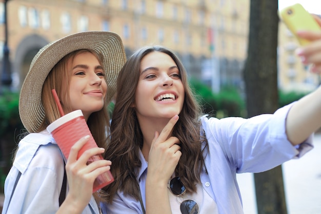 Dois amigos rindo, aproveitando o fim de semana juntos e fazendo selfie no fundo da cidade.