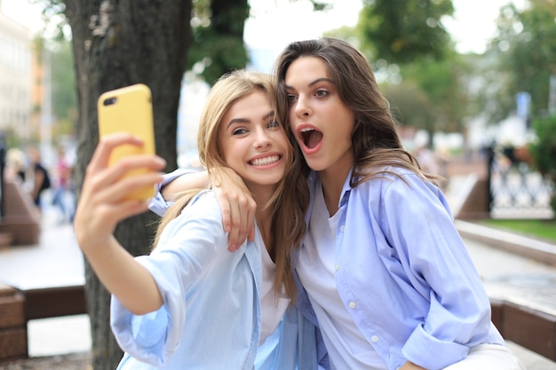 Dois amigos rindo, aproveitando o fim de semana juntos e fazendo selfie no fundo da cidade.