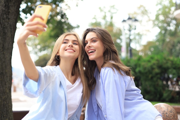 Dois amigos rindo, aproveitando o fim de semana juntos e fazendo selfie no fundo da cidade.