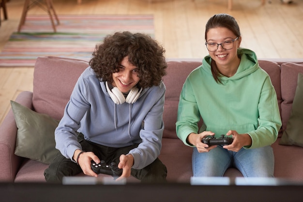 Dois amigos sentados no sofá jogando videogame online em casa