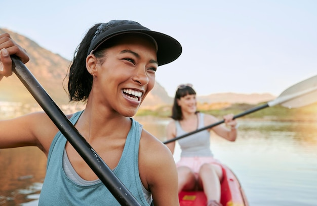 Dois amigos sorridentes andando de caiaque juntos em um lago durante as férias de verão mulheres brincalhonas sorridentes e felizes se unindo ao ar livre na natureza com atividade aquática se divertindo em um caiaque durante a recreação de fim de semana