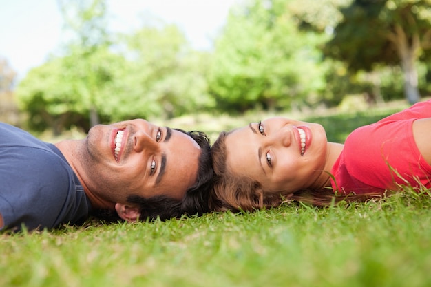 Dois amigos sorridentes olhando para o lado, enquanto deitem cabeça a cabeça