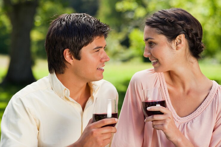Foto dois amigos sorrindo um para o outro enquanto guardam óculos de vinho