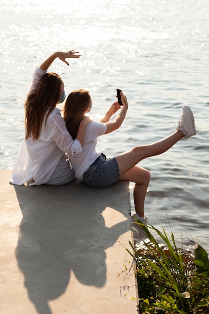 Dois amigos tirando uma selfie juntos à beira do lago