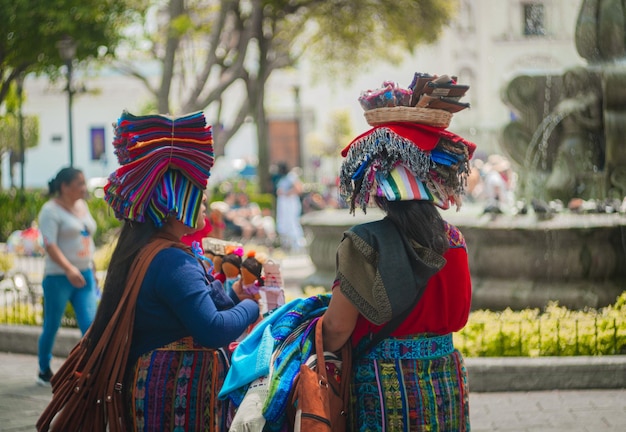 Dois amigos vendedores do Parque de la Antigua Guatemala vendem chapéus de tecido e artesanato tradicional