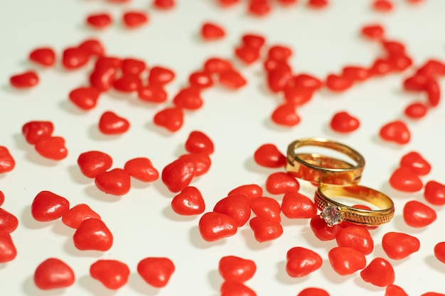 Foto dois anéis de casamento com vários corações pequenos na mesa branca