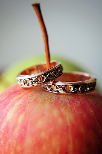 Dois anéis de casamento de ouro na maçã vermelha, close-up. o vintage soa para noivos, foco seletivo. conceito do casamento