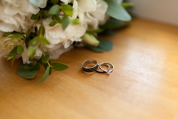 Dois anéis de casamento de platina na madeira com flores