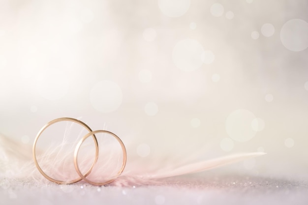 Foto dois anéis de casamento dourados e fundo suave de luz de penas