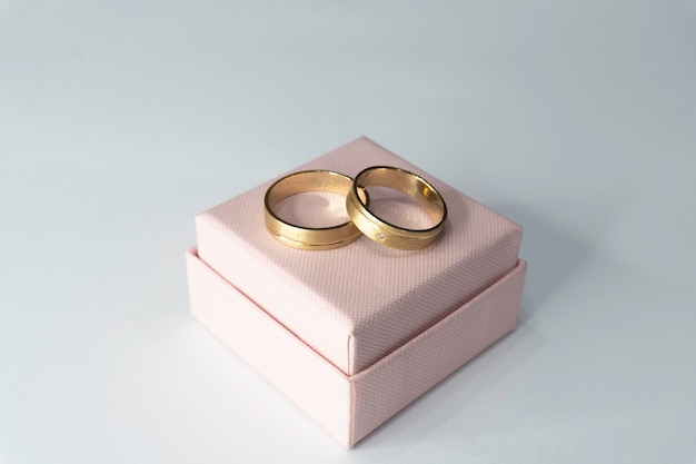 Dois anéis de ouro em uma caixa com fundo branco.