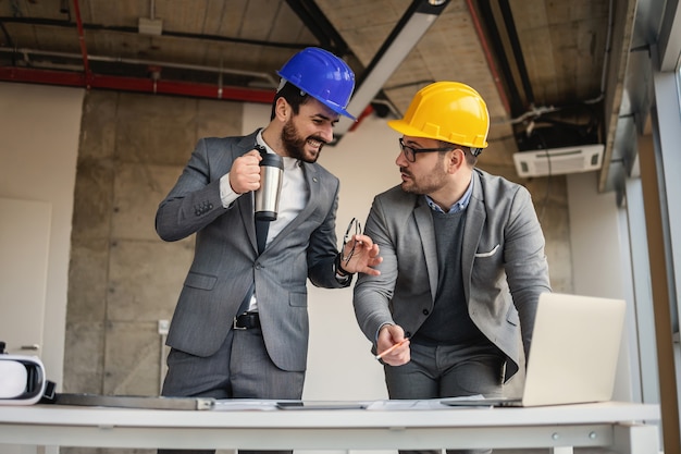 Dois arquitetos em construção em processo de construção e falando sobre um grande projeto.