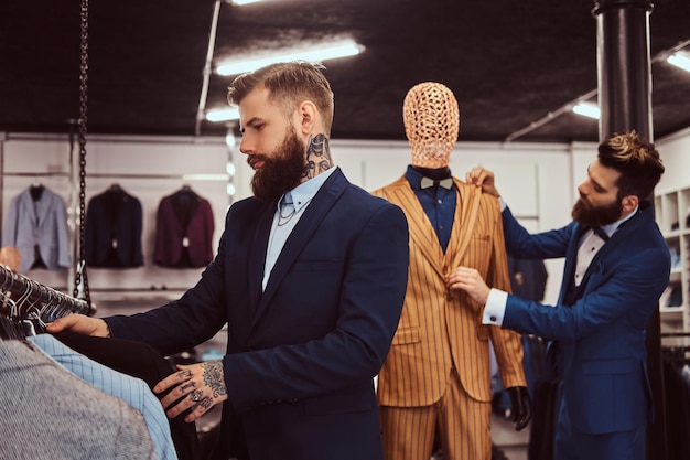 Dois assistentes de loja elegantes vestidos elegantemente trabalhando em uma loja de moda masculina.