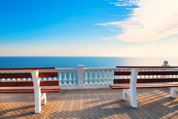 Dois bancos no terraço com vista mar ao pôr do sol. Bela vista do mar de verão, conceito de destino de viagem.