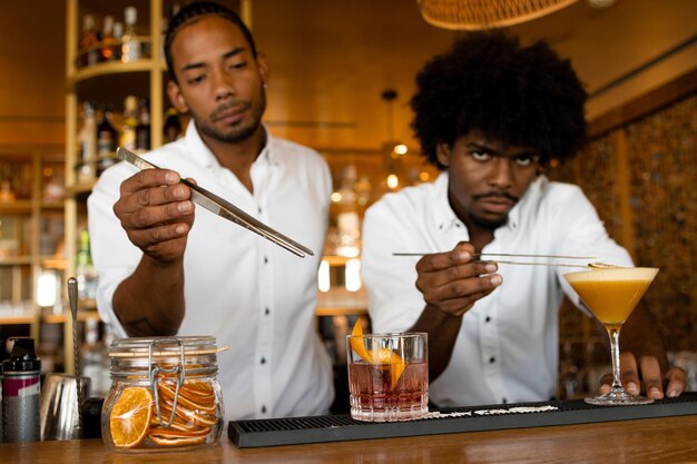 Dois bartenders latinos com cabelos encaracolados a fazer coquetéis.