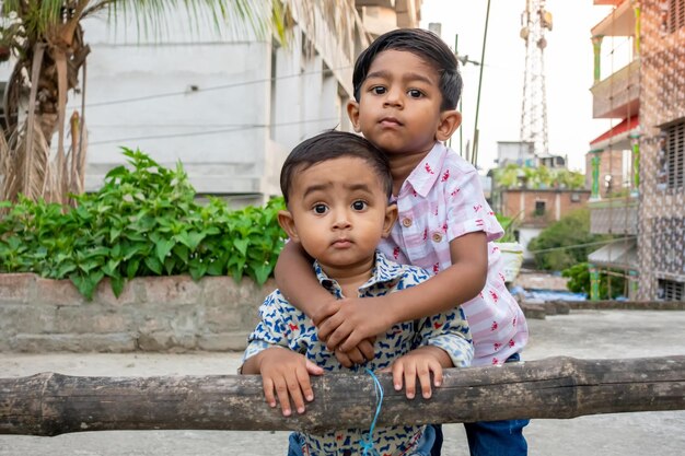 Dois bebês bonitos asiáticos parados no telhado Dois irmãos estão se abraçando e se acariciando