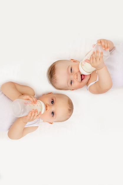 Dois bebês gêmeos, menino e menina, com uma garrafa de leite