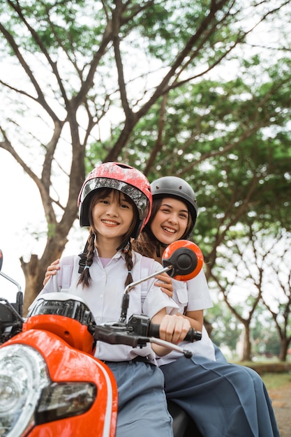 Dois belos alunos usando capacetes sorrindo enquanto andam de moto