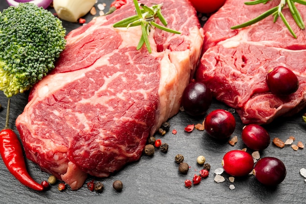 Dois bifes de carne em mármore cru com especiarias e legumes