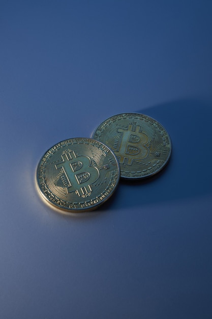 Dois bitcoins dourados isolados em close-up de fundo azul com espaço de cópia, conceito de crescimento e queda de criptomoeda