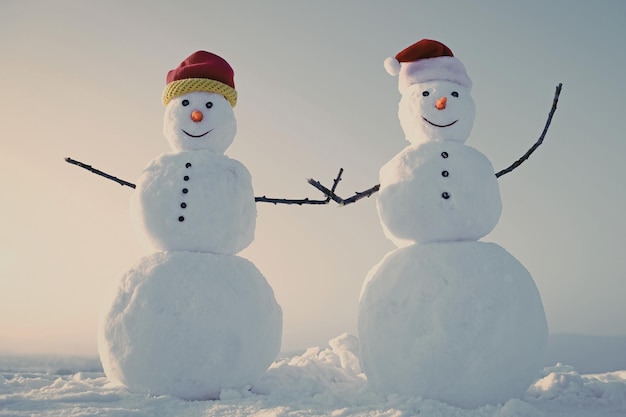 Dois bonecos de neve no inverno ao ar livre, ano novo, bonecos de neve com chapéu de Papai Noel