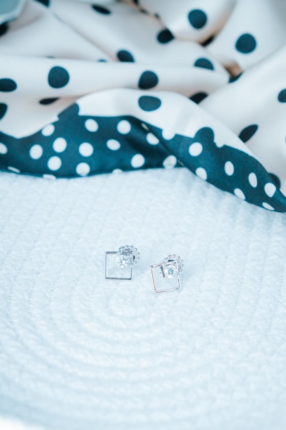 Dois brincos de diamante estão sobre um pano branco.