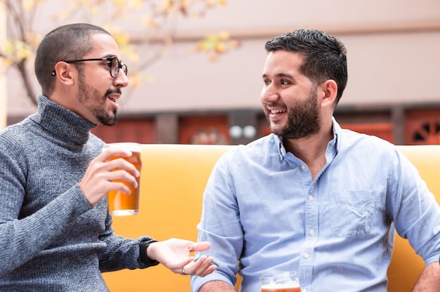 Dois caras curtindo uma tarde sentados do lado de fora de um bar bebendo cerveja artesanal