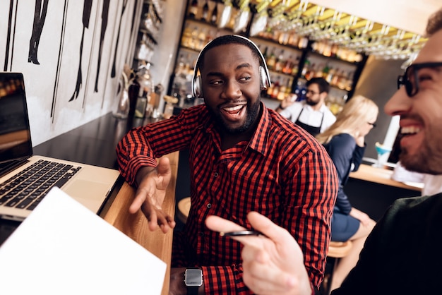 Dois caras estão sentados no bar com um computador.